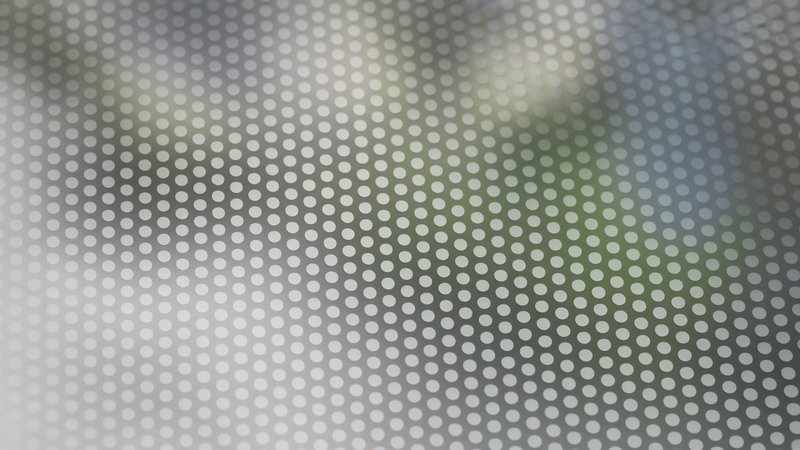 Close-up of perforated window film showing the small holes that make it see-through